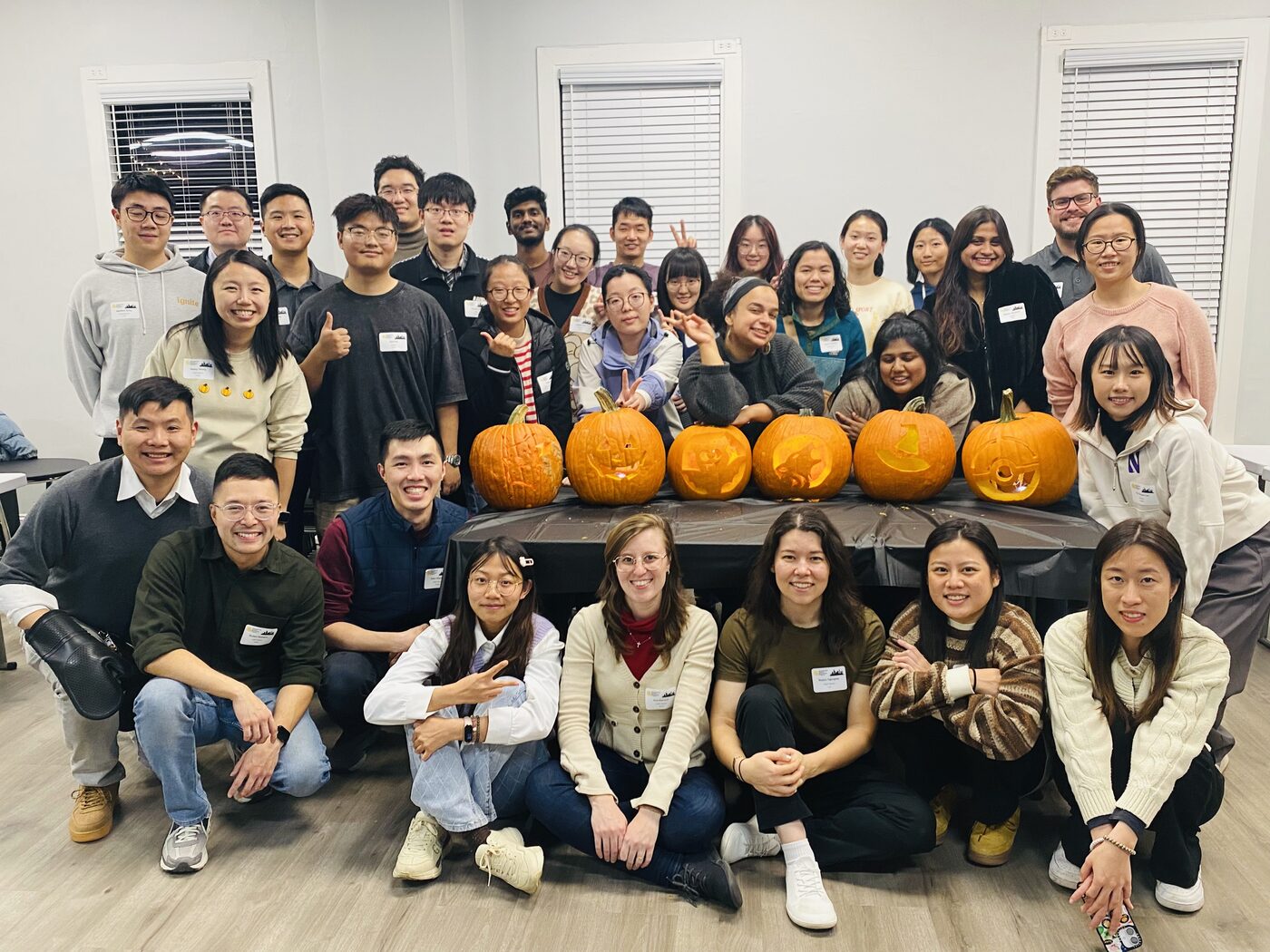ISMP students and mentors around a row of carved pumpkins at a Halloween party in Chicago