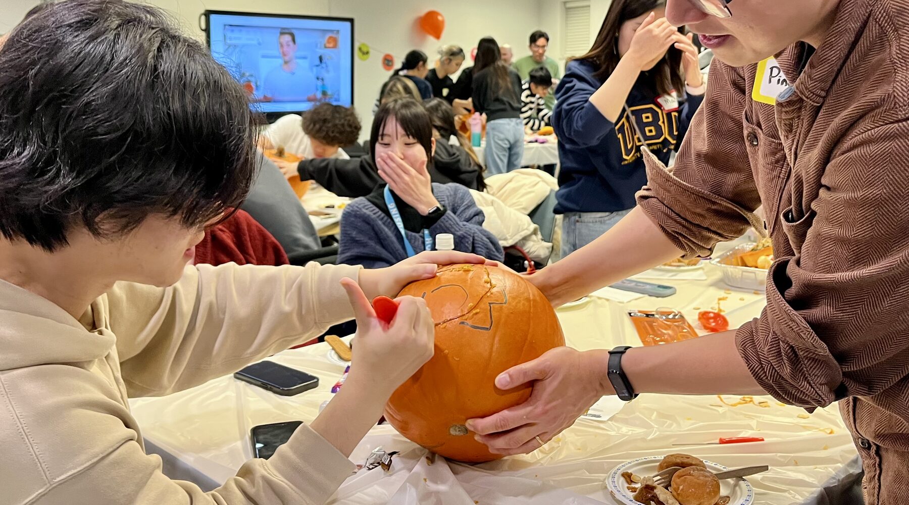 A student and her mentor carving a pumpkin together at an ISMP Halloween night